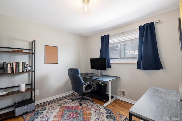 home office with baseboards, wood finished floors, and visible vents