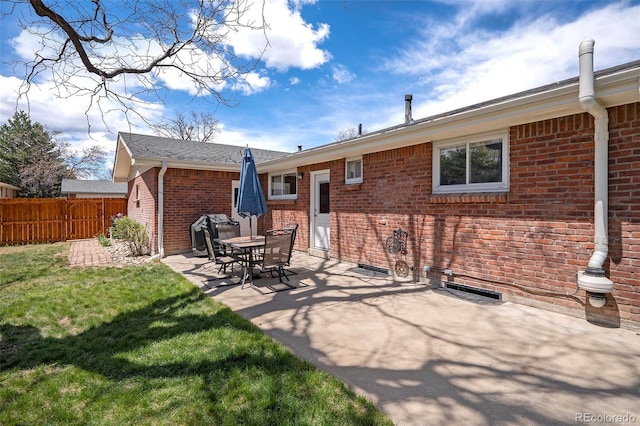 back of property with a yard, brick siding, fence, and a patio