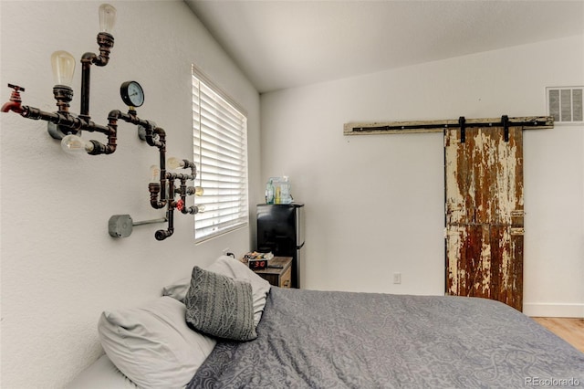 bedroom with a barn door and wood finished floors