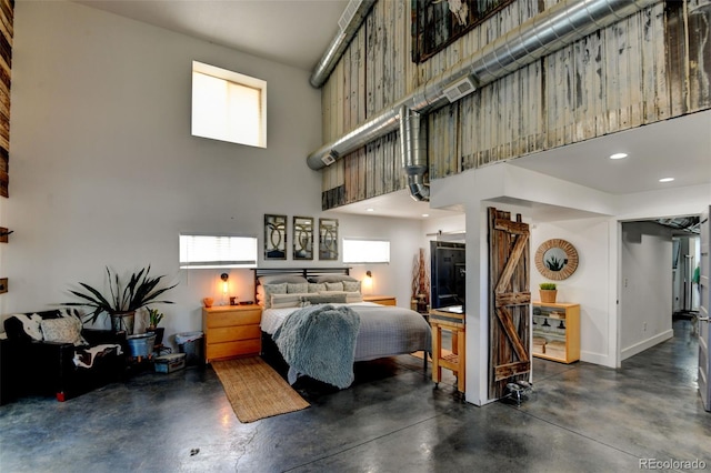 bedroom featuring finished concrete flooring, a towering ceiling, baseboards, and recessed lighting