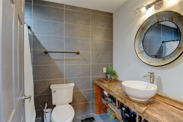 bathroom featuring a sink, tile walls, and toilet