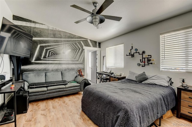 bedroom featuring lofted ceiling, wood finished floors, an accent wall, and a ceiling fan