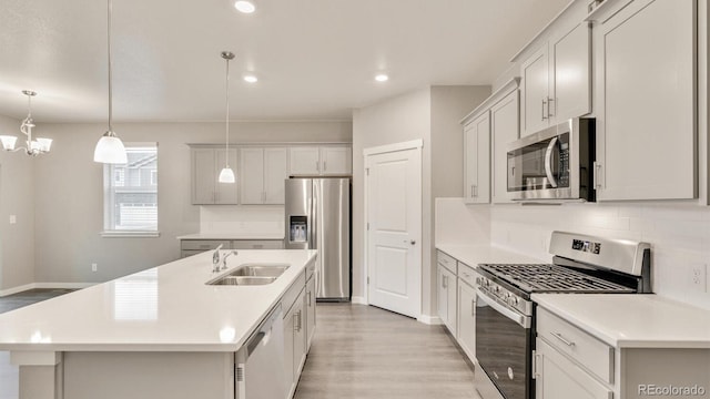 1144 Ridgefield Dr, Berthoud, CO 80513 - kitchen with appliances with stainless steel finishes, light wood-style flooring, light countertops, backsplash, and an island with sink