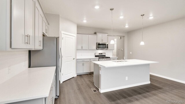 1144 Ridgefield Dr, Berthoud, CO 80513 - kitchen with appliances with stainless steel finishes, dark wood-type flooring, light countertops, an island with sink, and pendant lighting