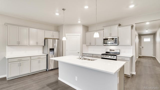 1144 Ridgefield Dr, Berthoud, CO 80513 - kitchen featuring stainless steel appliances, wood finished floors, a center island with sink, light countertops, and recessed lighting