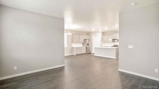 1144 Ridgefield Dr, Berthoud, CO 80513 - unfurnished living room with dark wood-style flooring and a chandelier
