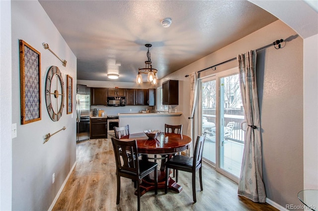 dining area with light hardwood / wood-style flooring and a textured ceiling