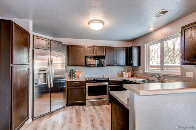 kitchen featuring sink, a textured ceiling, appliances with stainless steel finishes, dark brown cabinets, and light hardwood / wood-style floors