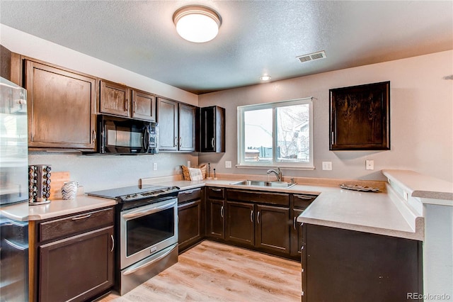 kitchen featuring sink, stainless steel stove, light hardwood / wood-style flooring, a textured ceiling, and dark brown cabinets