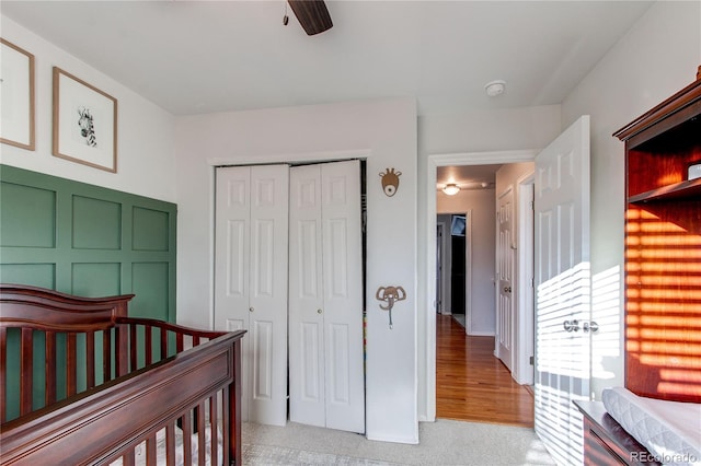 carpeted bedroom featuring a crib, a closet, and ceiling fan