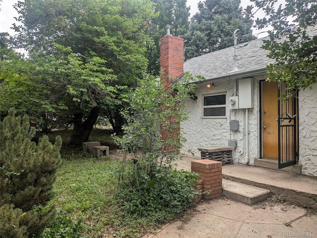 4209 Perry St, Denver, CO 80212 - doorway to property featuring a chimney, stucco siding, and a shingled roof