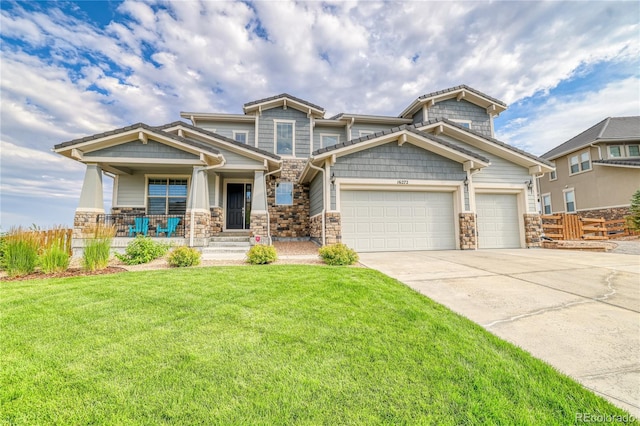 craftsman-style house with covered porch, a garage, and a front lawn