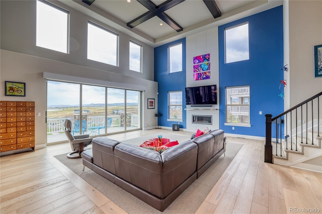 living room featuring beam ceiling, coffered ceiling, light hardwood / wood-style flooring, and a high ceiling