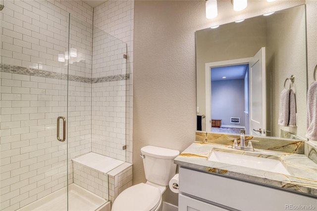 bathroom featuring vanity, toilet, and a shower with door