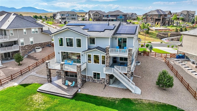 back of property featuring a mountain view, solar panels, and a patio area