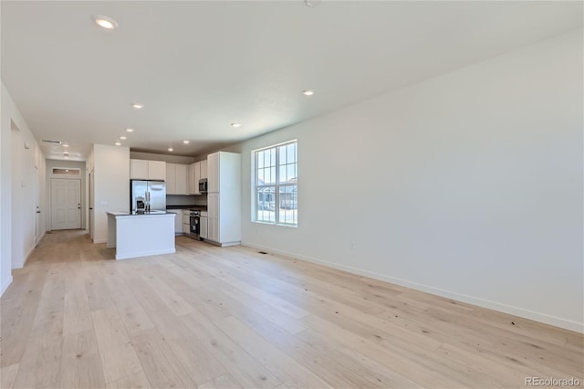 unfurnished living room with light wood-type flooring, baseboards, and recessed lighting