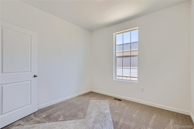 spare room featuring carpet floors, visible vents, and baseboards