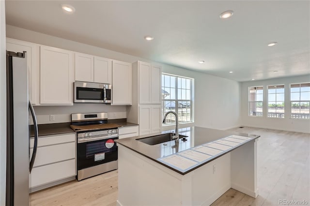 kitchen featuring stainless steel appliances, white cabinets, a healthy amount of sunlight, and a sink