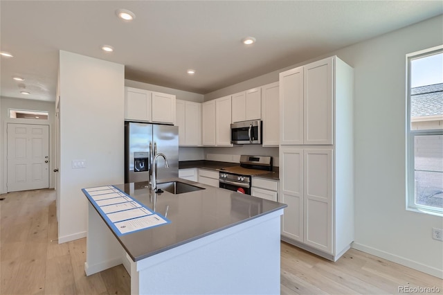 kitchen featuring stainless steel appliances, a sink, white cabinets, and a healthy amount of sunlight