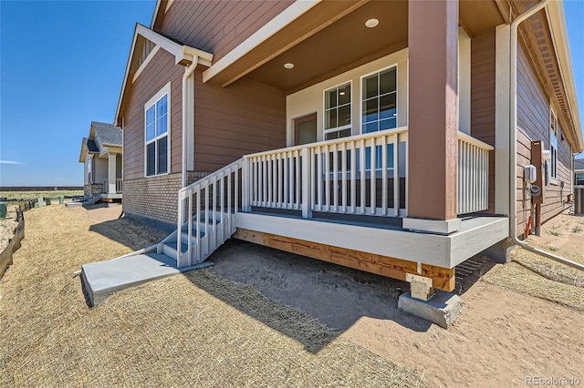 view of property exterior with a porch, central AC, and brick siding