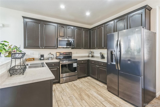 kitchen with dark brown cabinetry, stainless steel appliances, sink, and light hardwood / wood-style flooring