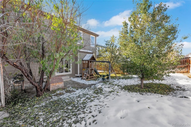 snowy yard featuring a playground