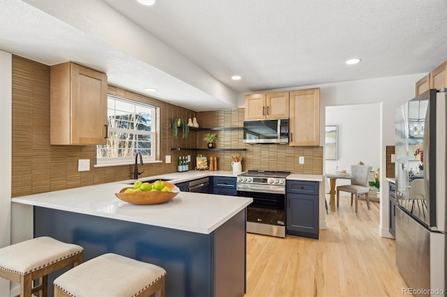 kitchen with gray cabinetry, light countertops, light brown cabinets, and stainless steel appliances