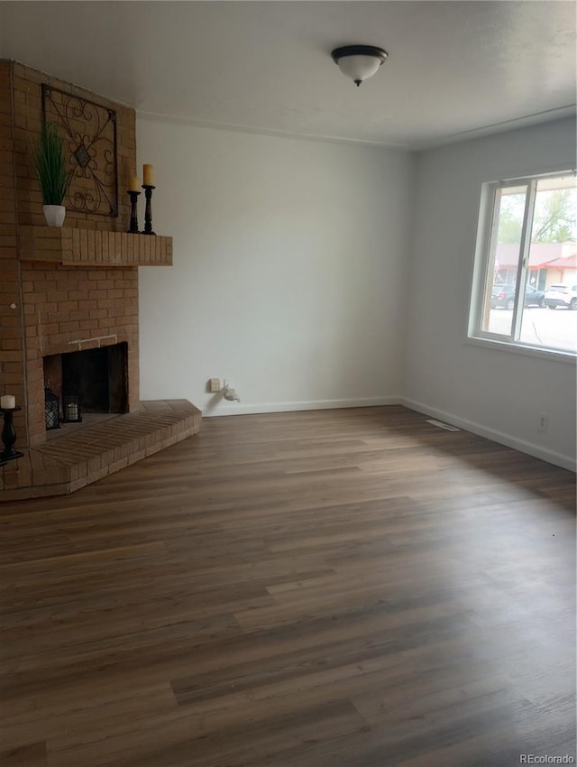 5640 E 67th Pl, Commerce City, CO 80022 - unfurnished living room featuring baseboards, a brick fireplace, and wood finished floors
