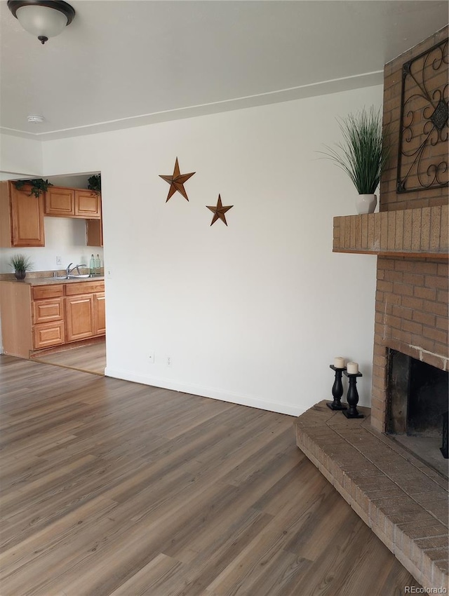 5640 E 67th Pl, Commerce City, CO 80022 - unfurnished living room featuring baseboards, a sink, wood finished floors, and a fireplace