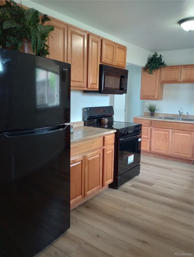 5640 E 67th Pl, Commerce City, CO 80022 - kitchen with light brown cabinetry, light wood-style floors, light countertops, a sink, and black appliances