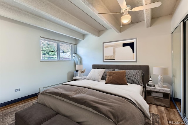 1265 Elizabeth St Unit 207, Denver, CO 80206 - bedroom featuring baseboard heating, wood finished floors, beamed ceiling, a closet, and a ceiling fan