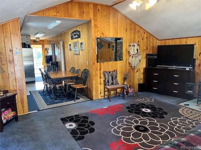 carpeted living room featuring lofted ceiling, wooden walls, and a ceiling fan