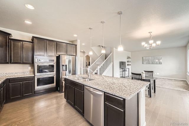 785 Iris St, Brighton, CO 80601 - kitchen with stainless steel appliances, dark brown cabinetry, light wood-style flooring, light stone countertops, and recessed lighting
