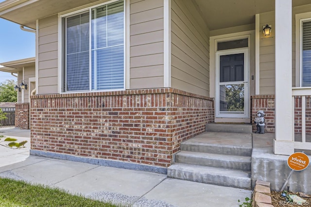 785 Iris St, Brighton, CO 80601 - doorway to property featuring covered porch and brick siding