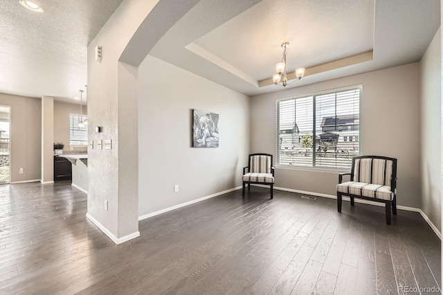 785 Iris St, Brighton, CO 80601 - living area with a chandelier, dark wood-style flooring, a tray ceiling, and a textured ceiling