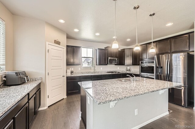 785 Iris St, Brighton, CO 80601 - kitchen featuring stainless steel appliances, dark wood-type flooring, dark brown cabinets, light stone countertops, and recessed lighting