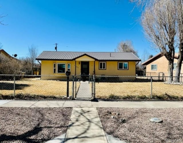 view of front of property with a fenced front yard, a gate, and metal roof