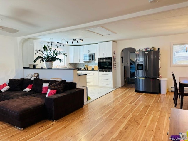 living area featuring light wood-type flooring and arched walkways