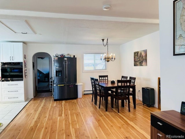 dining area featuring arched walkways, a baseboard radiator, light wood-style flooring, and an inviting chandelier