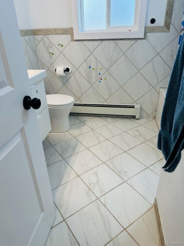 bathroom featuring toilet, a baseboard heating unit, and tile walls