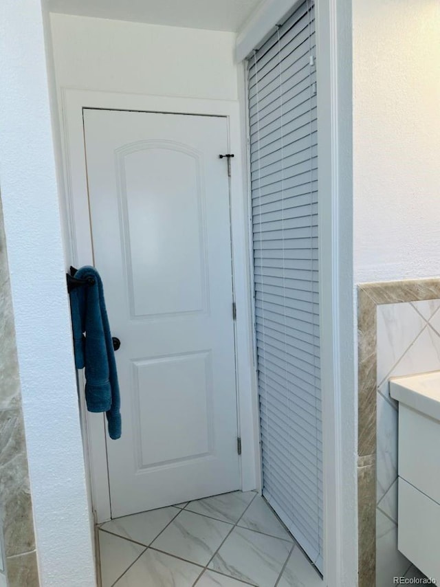 entryway featuring marble finish floor and tile walls