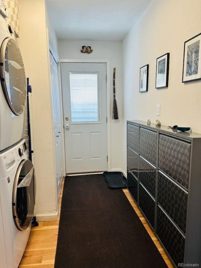 laundry room featuring laundry area, light wood-style flooring, baseboards, and stacked washer and clothes dryer