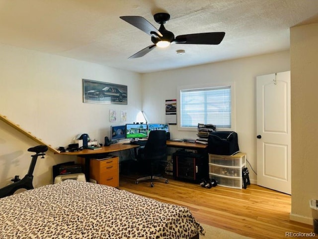 bedroom featuring ceiling fan, a textured ceiling, baseboards, and wood finished floors