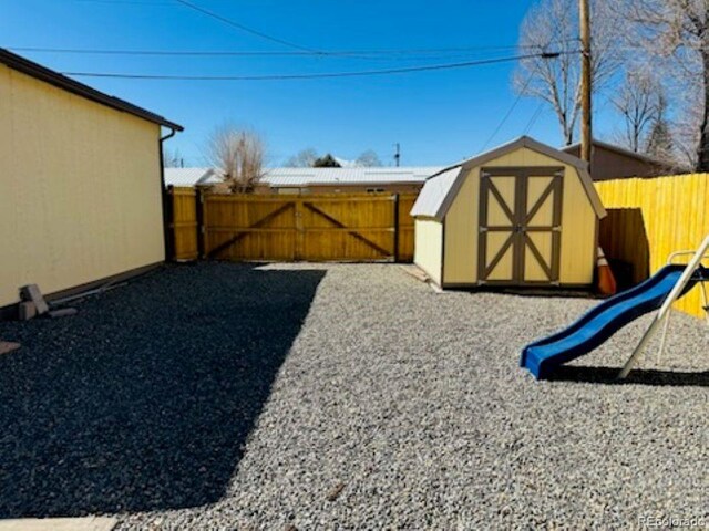 view of yard featuring a shed, a playground, a fenced backyard, and an outdoor structure