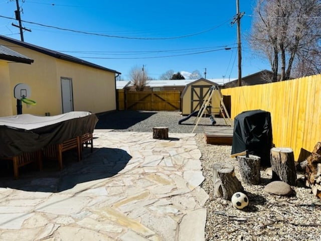 view of patio with a storage shed, a fenced backyard, and an outbuilding