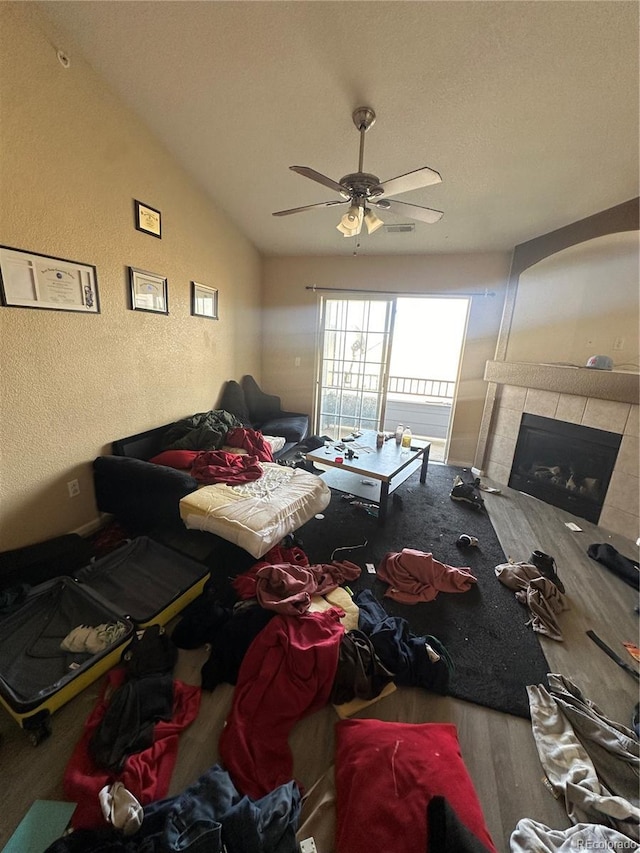 5255 Memphis St Unit 121, Denver, CO 80239 - living area featuring a textured wall, wood finished floors, a fireplace, a ceiling fan, and lofted ceiling