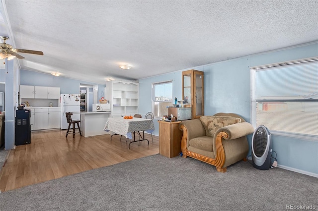 living room featuring ceiling fan, carpet floors, a textured ceiling, and vaulted ceiling