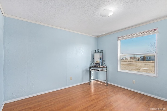 spare room with hardwood / wood-style floors, ornamental molding, and a textured ceiling