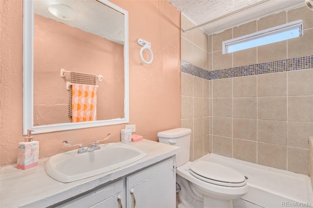 bathroom featuring tiled shower, vanity, a textured ceiling, and toilet