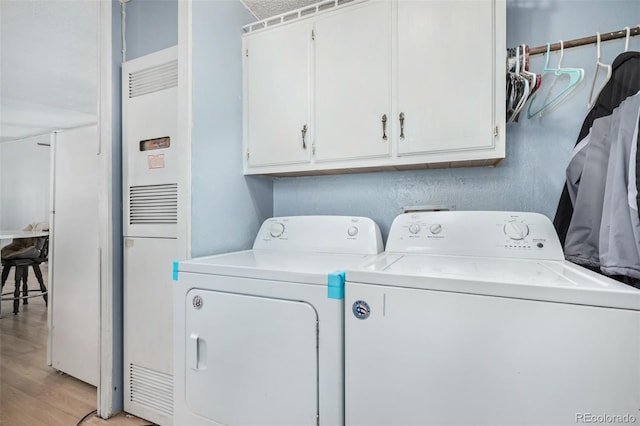 laundry area with cabinets, light wood-type flooring, and washing machine and clothes dryer